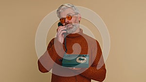 Bored tired mature man talking on wired vintage old-fashioned telephone fooling making silly faces