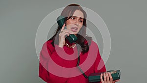 Bored, tired woman talking on wired vintage telephone fooling, making silly faces, unpleasant talk
