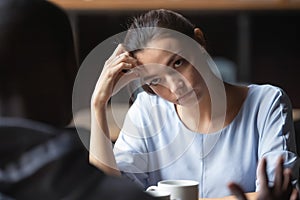 Bored unhappy girlfriend listening to African American boyfriend in cafe photo