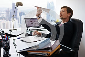 Bored White Collar Worker Throwing Paper Airplane In Office photo