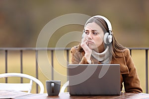Bored woman with headphones and laptop in a coffee shop