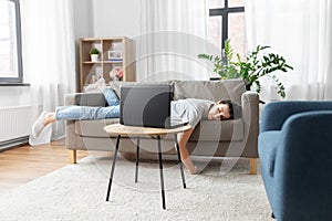 Bored woman with laptop lying on sofa at home