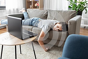 Bored woman with laptop lying on sofa at home