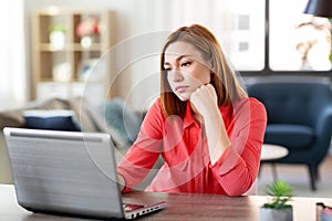 Bored woman with laptop working at home office