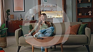 Bored woman looking mobile phone relaxing on comfortable sofa. Tired housewife