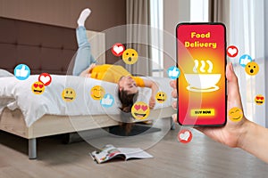 A bored woman is lying on the bed. Hand with a smartphone on the right. The concept of online food ordering with home delivery