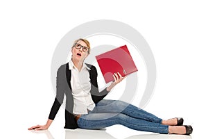 Bored woman sitting on the floor with ring binder.