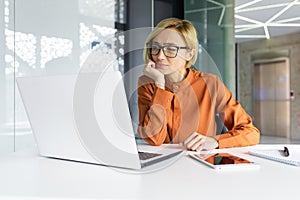 Bored woman working inside office at workplace, boring routine work in blonde business woman, using laptop while sitting