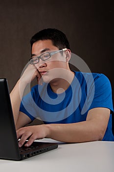 Bored young asian man working with his computer