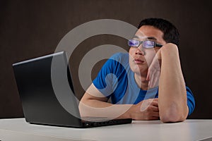 Bored young asian man working with his computer photo