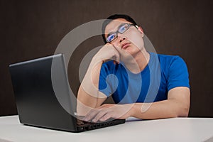 Bored young asian man working with his computer