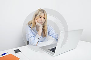 Bored young businesswoman using laptop at desk in office