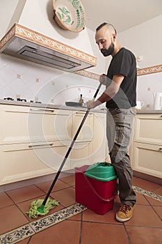 Bored young hispanic man mopping the floor