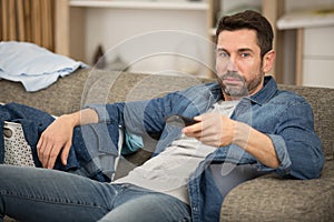 Bored young man holding tv remote control