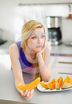 Bored young woman eating slice of melon