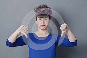 Bored young woman with thumbs down blowing out her cheeks