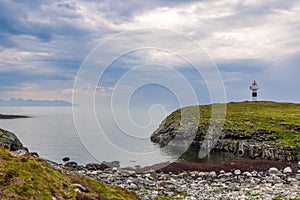 Borhella lighthouse on a verdant outcrop, with Norway\'s rugged coastline and a pebbled beach