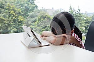 Boring asian Chinese little girl playing tablet computer