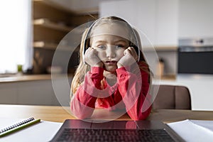 Boring Content. Upset little girl in headphones looking at laptop screen, webcam pov