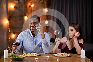 Boring Date. Black guy talking on cellphone in restaurant, ignoring his girlfriend