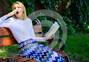 Boring literature. Woman yawning blonde take break relaxing in garden reading book. Girl sit bench relaxing with book