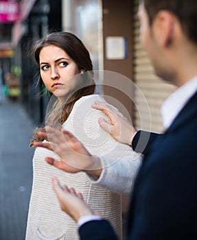 Boring male person accosting to female at crowded street