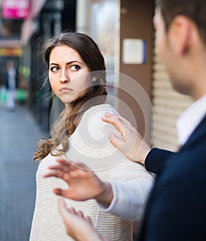 Boring male person accosting to female at crowded street