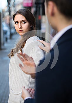 Boring male person accosting to female at crowded street