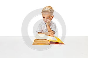 Boring pupil, boy of elementary class sitting with opened textbook, doing homework. Child study and learn for preschool