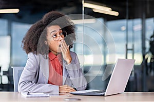 Boring daily routine work inside office, business woman yawning, working at workplace with laptop, overtired woman photo