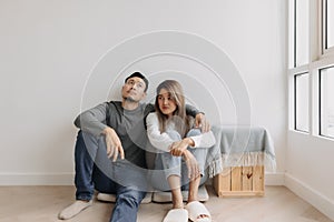 Boring and tired faces of lover sit on the floor of empty room.