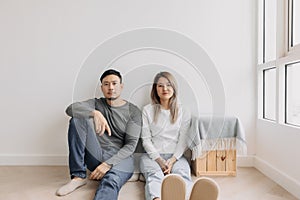 Boring and tired faces of lover sit on the floor of empty room.