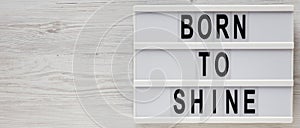 `Born to shine` words on a lightbox on a white wooden background, top view. Overhead, from above, flat lay. Space for text