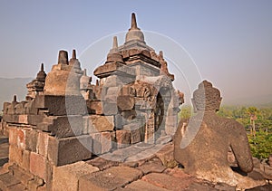 Borobudur during late sunrise with misty feeling among the forest in the background