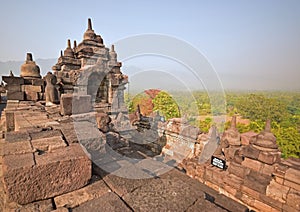 Borobudur during late sunrise with misty feeling among the forest in the background