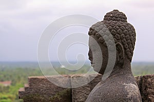 Buddha statue overlooking surroundings at Borobudur temple at sunrise in Java Indonesia