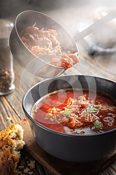 Borsch is poured into a bowl from a ladle from which steam, a traditional Ukrainian vegetable soup made from beets