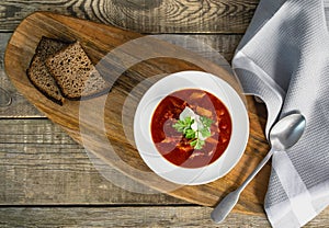 Borsch soup in a bowl, tasty and healthy soup with garlic, red beet. Organic traditional russian soup on wooden table.