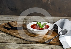 Borsch soup in a bowl, tasty and healthy soup with garlic, red beet. Organic traditional russian soup on wooden table.