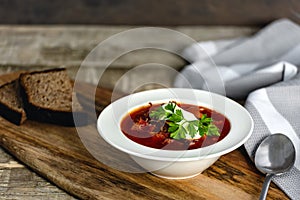 Borsch soup in a bowl, tasty and healthy soup with garlic, red beet. Organic traditional russian soup on wooden table.