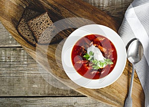 Borsch soup in a bowl, tasty and healthy soup with garlic, red beet. Organic traditional russian soup on wooden table.