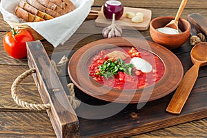 Borsch - traditional Ukrainian and Russian beetroot soup on dark wooden background. Served with rye bread, garlic and salt on