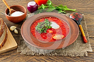 Borsch - traditional Ukrainian and Russian beetroot soup on dark wooden background. Served with rye bread, garlic and salt