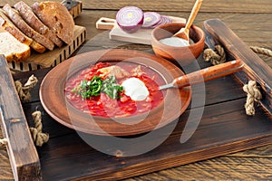 Borsch - traditional Ukrainian and Russian beetroot soup on dark wooden background. Served with rye bread, garlic and salt on