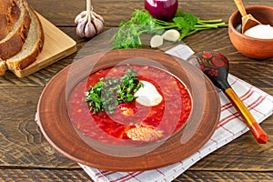 Borsch - traditional Ukrainian and Russian beetroot soup on dark wooden background. Served with rye bread, garlic and salt