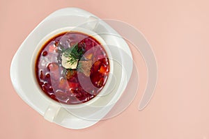 Borsch in white plate isolated on white. Beetroot soup on pink b