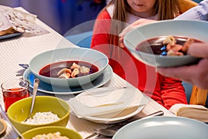 Borscht, borsch with ravioli, red beet soup, traditional Polish Christmas meal, dish served on the family table, detail, closeup.