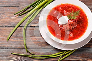 Borscht with sour cream and herbs on a wooden background