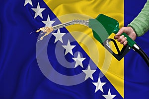 BOSNIA AND HERZEGOVINA flag Close-up shot on waving background texture with Fuel pump nozzle in hand. The concept of design