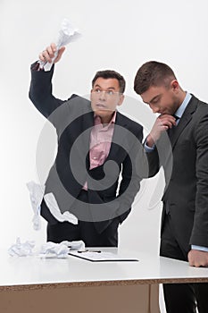 Boss angry with young employee sitting at desk